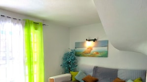 A living room with a sofa, a small table, and a painting on the wall.
