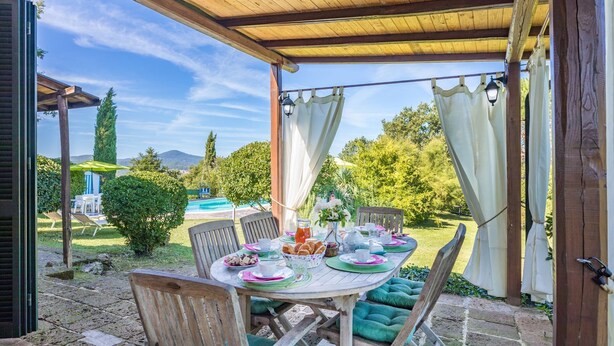 An outdoor patio with a wooden table set for a meal, surrounded by chairs. - lovely ground floor cottage, sleeps 6 set in a tranquil ,private and panoramic position – completely (MONTICIANO)