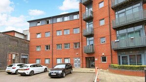 A multi-story red brick building with a parking area. There are three cars parked in front. - Broad Gauge Apartments (Wolverhampton)