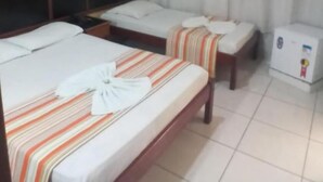 A hotel room with two beds, a small table, a nightstand, a refrigerator, and a curtain. - Hotel Bell Vale (São José dos Campos)