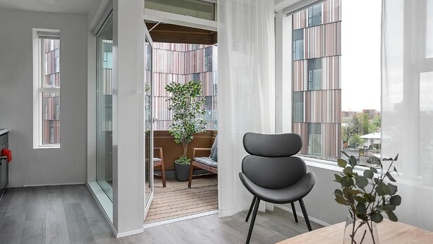 Ein modernes Interieur mit Essbereich, Blick auf einen Balkon mit Pflanzen und einem großen Fenster.