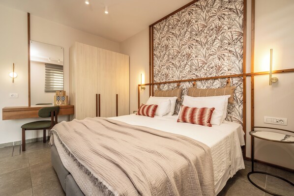 Une chambre à coucher avec un grand lit, un bureau avec une chaise, un miroir et un mur orné d’un motif.