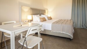Una habitación de hotel con una cama, una mesa, dos sillas y una lámpara.