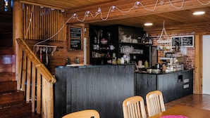 A rustic interior with a wooden staircase, a bar area with shelves, and a seating area with tables. - Valkeisen Loma (Ahtari)