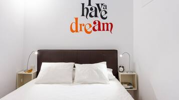 A neatly made bed with white bedding, a dark headboard, and a wall decal that reads "I have a dream".