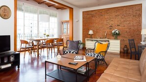 A living room with a dining area, a TV, and a brick wall. - Casa Cosi - Mallorca 1 (Barcelona)