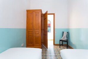 Une chambre avec deux lits, une armoire en bois et une chaise.