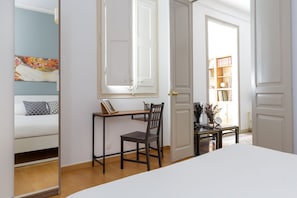 Een slaapkamer met een bed, een bureau met stoel, en een boekenkast.