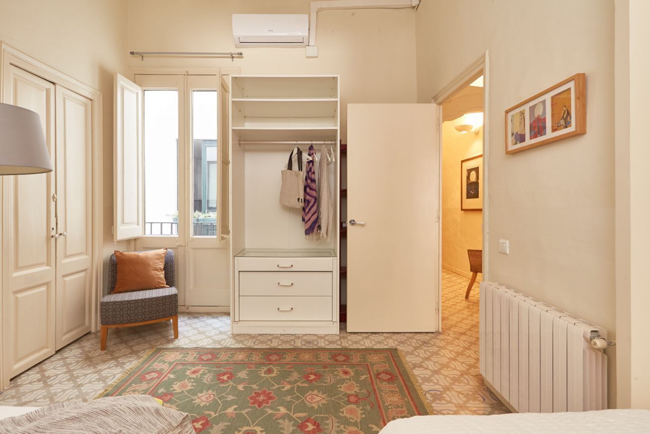 A bedroom with a bed, a chair, a wardrobe, and a radiator.