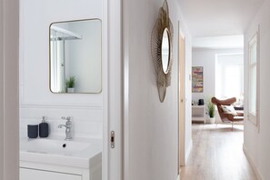 A modern bathroom with a white vanity, a large mirror, and a decorative wall mirror. - Casa Cosi - Eixample 2 (Barcelona)