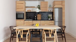 A modern kitchen with wooden cabinets, a black brick backsplash, stainless steel appliances, and a wooden dining table with chairs. - Casa Cosi - Eixample 2 (Barcelona)