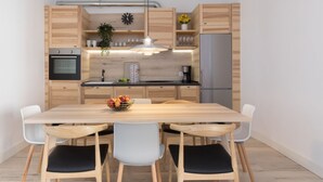A modern kitchen with wooden cabinets, a stainless steel refrigerator, and a dining table with chairs.