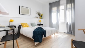 A modern bedroom with a bed, bedside tables, a desk, and a chair.