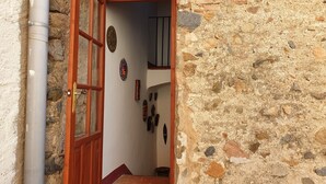 An open wooden door leading into a room with stone walls and a tiled floor. - Family apartment located between the Priorat wine district and the beach in Cambrils (Duesaigües)