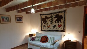 A cozy living room with a white sofa, two side tables with lamps, a patterned rug, and a wall tapestry. - Family apartment located between the Priorat wine district and the beach in Cambrils (Duesaigües)