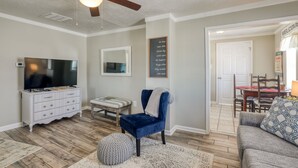 A living room with a ceiling fan, a flat-screen TV, a white dresser, a blue velvet chair, and a gray couch. - Country cottage beside stocked pond on 40 acres and Blue ridge Mountain View (Front Royal)