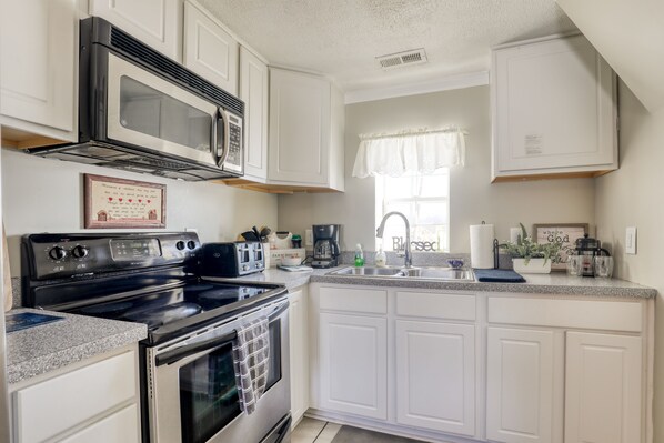A kitchen with white cabinets, a black stove, a microwave, a toaster, and a sink with a window above it. - Country cottage beside stocked pond on 40 acres and Blue ridge Mountain View (Front Royal)