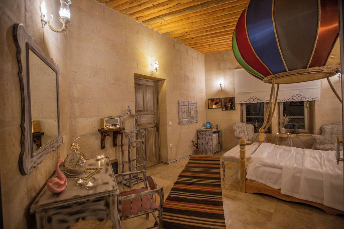 A room with a bed, a wooden ceiling, a mirror, a lamp, and a wall-mounted radio.