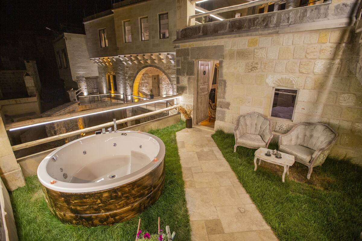 A spa area with a hot tub, a stone wall, and a seating area with two chairs.