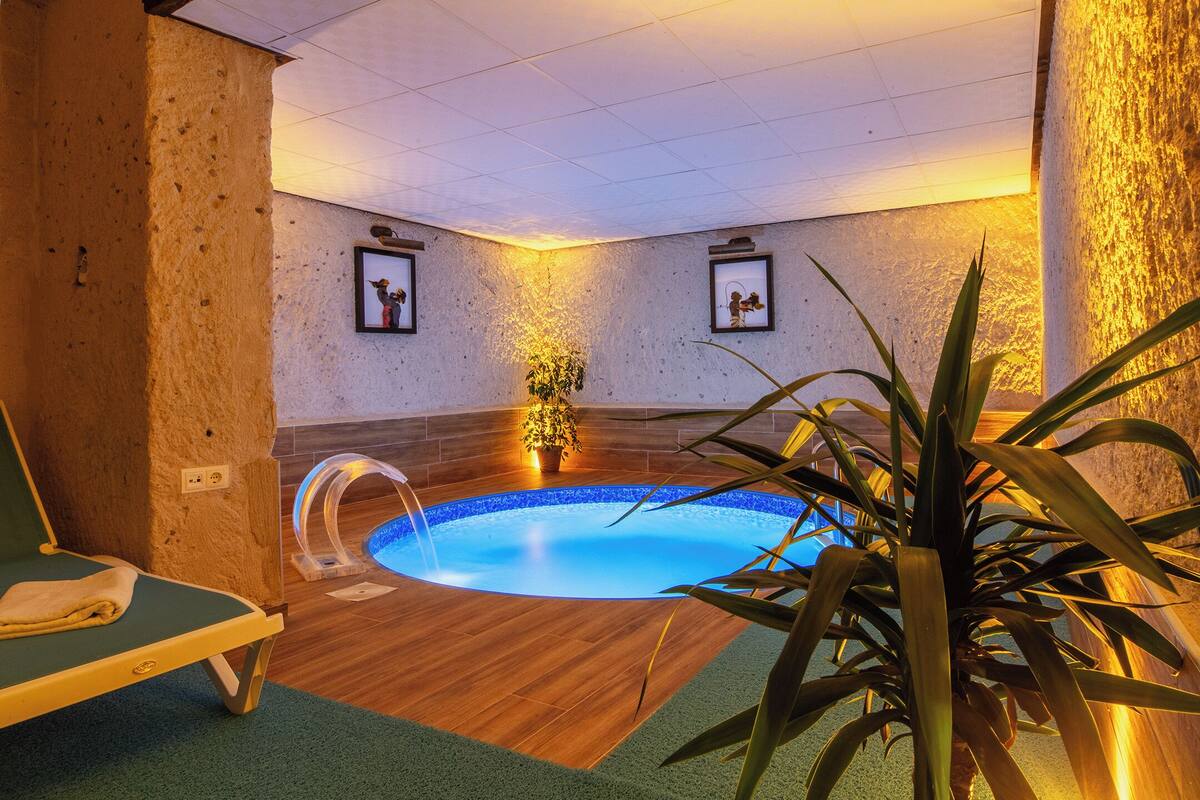 A spa area with a small pool, a lounge chair, and framed pictures on the wall.