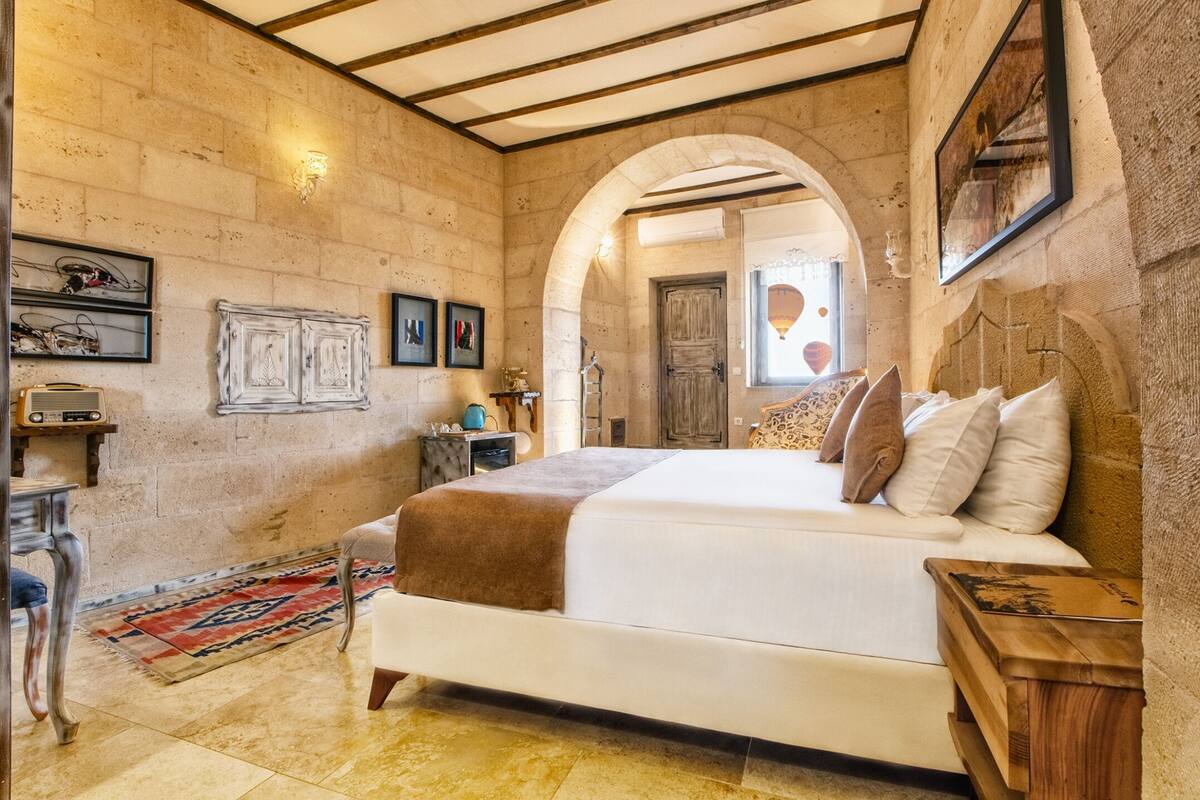 A bedroom with a large bed, a wooden nightstand, a radio, and a rug.