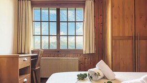 Une pièce en bois avec un lit, un bureau et une fenêtre avec des rideaux.