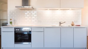 Una cocina moderna con armarios blancos, horno empotrado y campana de acero inoxidable.