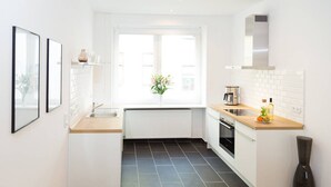 Una cocina moderna con armarios blancos, un ventanal grande y piso de baldosas negras.