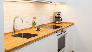 A modern kitchen with a wooden countertop, stainless steel appliances, and white cabinetry.