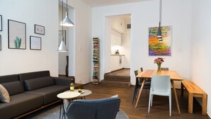 A modern living room with a sofa, a round table, and a dining area with a wooden table and chairs.