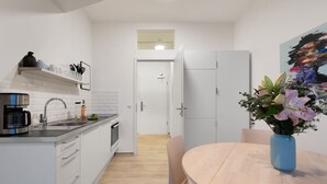 Ett modernt kök med en kaffebryggare, en diskho och ett skåp. Där finns också ett matbord med stolar och en vas med blommor.