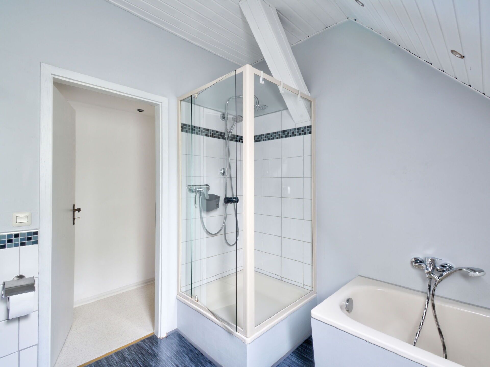 A modern bathroom with a glass-enclosed shower, a bathtub, and a toilet.