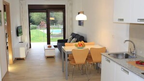 A modern kitchen with a dining area, a large window, and a view of a swimming pool.