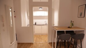 Une cuisine moderne avec des meubles blancs, un plan de travail en bois et un coin bar avec des tabourets.