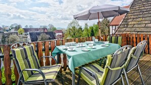 Ein Essbereich im Freien mit einem Tisch, gedeckt für vier Personen, umgeben von Stühlen mit gestreiften Kissen.