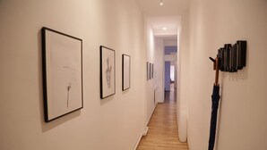 A hallway with framed artworks on the walls and a wooden floor.