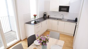 Une cuisine moderne avec des meubles blancs, un plan de travail noir et un coin repas avec une table dressée pour deux personnes.