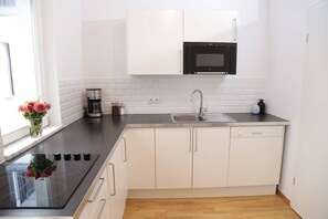 Enjoy cooking in this well-equipped kitchen with a black induction cooktop, stainless steel sink, and microwave.