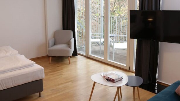 Une chambre d’hôtel moderne équipée d’un lit, d’un canapé, d’une chaise, d’une petite table et d’un téléviseur.