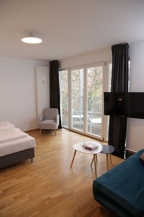 Relax in this serene space with a large bed, sofa, and chair, offering a view of the outdoors.