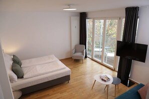 Relax in a spacious room with a large bed, flat-screen TV, and sliding glass door leading to a balcony with an outdoor view.