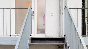 Una escalera metálica con barandilla que lleva a una puerta con paneles de vidrio esmerilado.