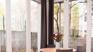 Una sala de estar moderna con una mesa redonda de madera, sillas grises, una mesa blanca para café y un sofá.