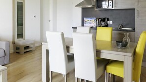 A modern kitchen with white and yellow chairs, a dining table, and a microwave above the counter. - Lovely apartment for 6 guests with WIFI, pool, TV, terrace and pets allowed (Biscarrosse)