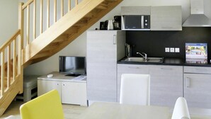A modern kitchen with a wooden staircase, a microwave, a sink, and a television. - Beautiful apartment for 8 guests with WIFI, pool, TV, terrace and pets allowed (Biscarrosse)
