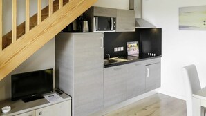 A compact kitchen with grey cabinets, a microwave, a kettle, and a small TV on a cabinet. - Beautiful apartment for 8 guests with WIFI, pool, TV, terrace and pets allowed (Biscarrosse)