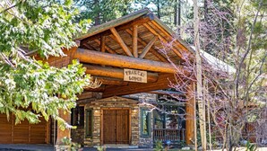Una cabaña rústica con fachada de piedra, puertas de madera y un letrero que dice 'TRAIL LODGE'.