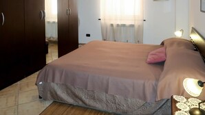 A bedroom with a bed, a nightstand, a lamp, a framed picture, and a wardrobe. - Nice apartment for 4 people with WIFI, A/C, TV and terrace (Civezza)