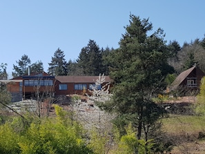 Ein zweistöckiges Haus mit rotem Ziegeldach, umgeben von dichtem Wald.