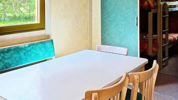 A room with a white table, green cushioned benches, and a window with a view of greenery.